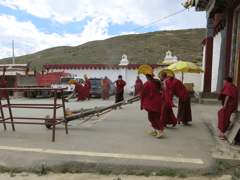 Trúbiaci budhistickí mnísi pred vstupom do kláštora v meste Litang v Tibete.